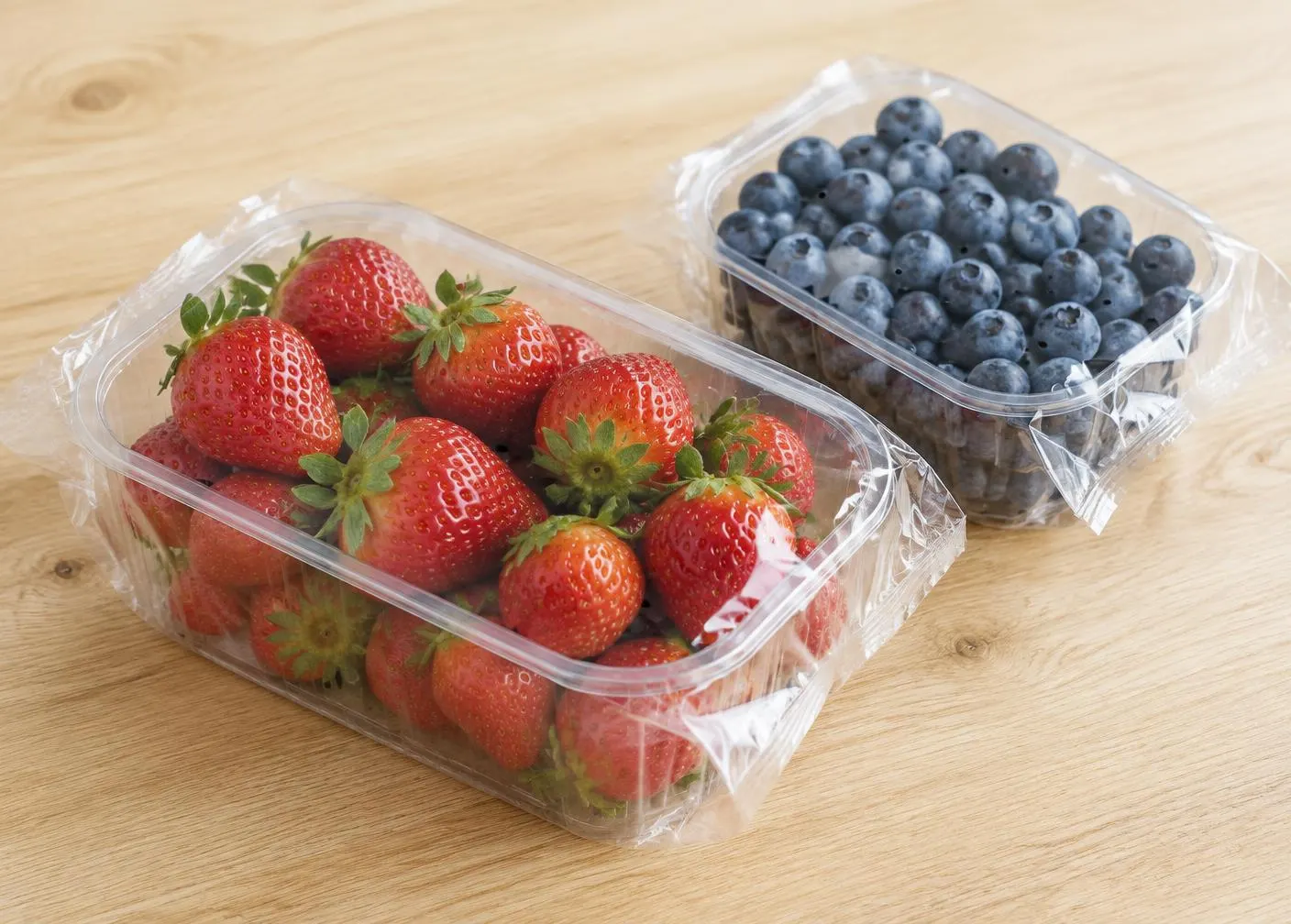 Erdbeeren und Heidelbeeren in Schalen mit transparenter Flowpack-Umverpackung