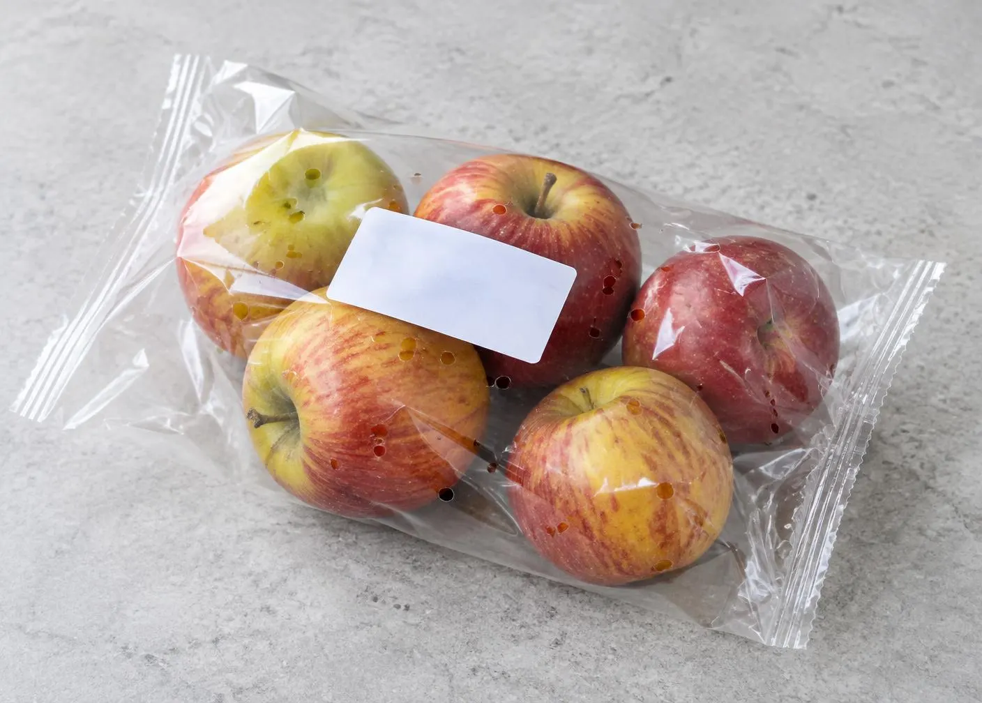 Äpfel unterschiedlicher Grösse direkt in perforierter transparenter Folie mit Etikett